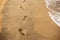 Children footprints in the sand. Human footprints leading away from the viewer. A row of footprints in the sand on a beach in the