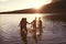 Children With Friends Enjoying Evening Swim In Countryside Lake