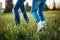 Children friends walking on meadow. Closeup of kids legs in jeans on grass. Outdoors fun summer seasonal children activity.