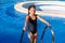 Children girl on the blue pool stairs black swimsuit