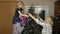 Children girl with elderly couple grandparents decorating artificial Christmas pine tree at home