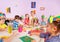 Children glue paper crafts together with teacher