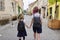 Children going to school, two girls sisters holding hands, back view