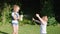 Children with good mood at park, girl use spray bottle with water while playing with little boy on green lawn