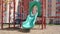 Children green plastic slide for kids in empty building yard