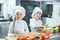 Children grind vegetables in the kitchen of a restaurant.