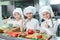 Children grind vegetables in the kitchen of a restaurant.