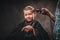 Children hairdresser with the trimmer is cutting little boy against the dark background. Cute preschooler boy getting