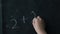 Children is hand writes an example in chalk on a black background.