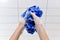 Children hands with a blue washcloth in foam against the background of a white tile