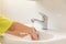 Children hands washed under running water in bathroom sink.