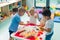 children having fun at the nursery and making figures with kinetic sand and plastic toys