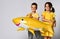 Children hold a balloon in the shape of a yellow shark fish, celebrate the holiday, smiling widely, stand on a light background,