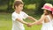 Children hold hands and start to circle together in the summer park. Slow motion