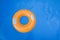 Children inflatable orange swimming ring with white handles floating in blue pool. Top view, close-up. Copy space for text