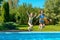 Children jump to swimming pool water and have fun, kids on family vacation
