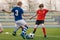 Children Kicking Football Ball. Boys Play Soccer on Grass Field. Stadium Tribune and Seats in the Background