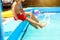Children kicking make splash in the pool in the summer.