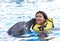 Children kissing dolphin in pool