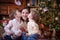 Children kissing their mother under Christmas tree