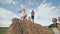 Children launch airplanes while standing on a stack of straw in front of their parents.