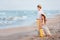 Children look in the sea.The girl and the boy are sitting on a yellow suitcase on the beach