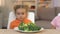 Children looking with disgust at broccoli, refusing to eat healthy vegetables