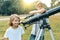 Children looking with interest in a telescope to the sky