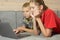 Children looking at a laptop while lying on the couch at home. brother and sister on remote online training