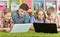 Children lying on floor with green carpet and looking at modern laptops