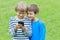 Children with mobile phone outdoor. Two boys smiling, looking to screen, playing games or using application. Technology