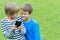 Children with mobile phone. Two boys smiling, looking to screen, playing games or using application. Outdoor. Technology