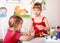 Children molding plasticine in playroom.