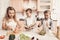 Children with mother in kitchen. Kids are helping mother to make salad.