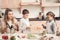 Children with mother in kitchen. Mother is helping kids prepare vegetables for salad.