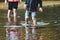 Children paddle in a stream of water outside during a sunny day out together