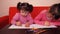 Children paint pencils. Two little girls draw on paper with crayons.