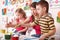 Children painting with teacher in art class.