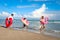 Children with parent wearing colorful inflatable swim ring running on summer beach, kids and adult on tropical sand beach, happy