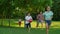 Children with parents running in summer park. Joyful family playing in meadow