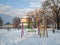 Children park and swing on winter day covered in snow during sunny day in suburb holidays winter season in suburbs