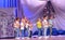 Children perform a dance on stage at a festive concert.