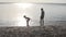 Children play on the beach by the lake at sunset, a little girl splashes water