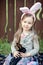 Children play with real rabbit. Laughing child at Easter egg hunt with white pet bunny. Little toddler girl playing with animal in