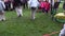 Children play sack race in city park with big people audience