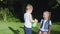 Children play with water, boy sprinkles with spray on girl on background of trees during summer relaxation