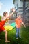 Children playing with garden sprinkler. Brother and sister running and jumping. Summer outdoor water fun in backyard