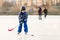 Children, playing hockey and skating in the park on frozen lake, wintertime on sunset