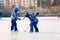 Children, playing hockey and skating in the park on frozen lake, wintertime on sunset