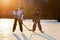 Children, playing hockey and skating in the park on frozen lake, wintertime on sunset